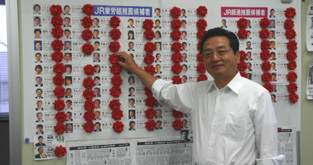 当選した推薦候補者に赤いバラを付ける、本部・千葉委員長